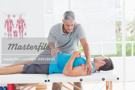 Doctor stretching a young man back in medical office
