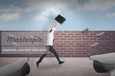 Businessman leaping with his briefcase against blue sky over a brick wall