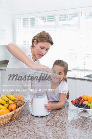 Mother and daughter making a smoothie at home in kitchen