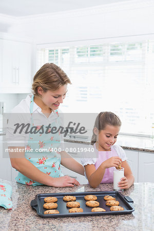 Mother and daughter with hot fresh cookiesat home in kitchen