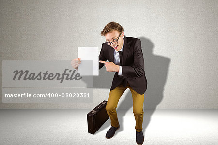 Young geeky businessman holding page against grey room