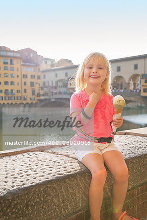 Portrait of happy baby girl eating ice cream near ponte vecchio in florence, italy