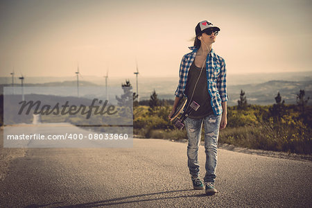 Beautiful young woman walking and holding a skateboard