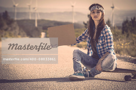 Beautiful young woman sitting over a skateboard