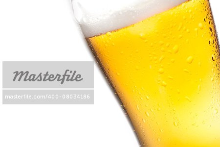 detail of tilted glass of fresh beer with drops on white background, with space for text