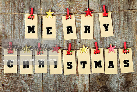 Merry Christmas lettering with clothes-peg in shape of train and stars on old wooden background
