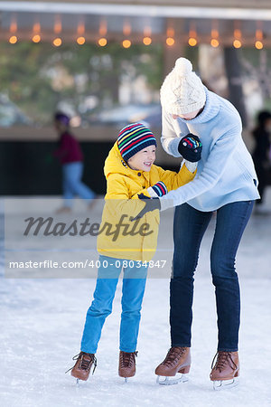 happy mother and her little son having fun ice skating together at winter