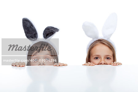 Kids with bunny ears peeking from beneath the table - waiting for the easter rabbit