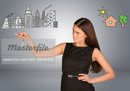 Woman making choice between city and country, looking at keys in her hand, on gray background