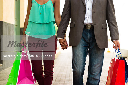Black tourist heterosexual couple walking in the streets of Casco Antiguo in Panama City with shopping bags. Cropped view of man and woman holding hands