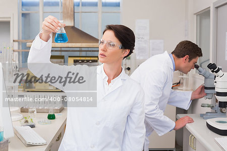 Scientists working with microscope and beaker in laboratory