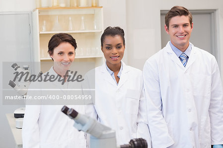 Smiling scientists team looking at camera in the laboratory