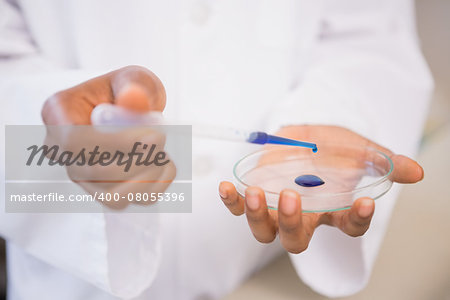 Scientist examining blue fluid in petri dish in laboratory