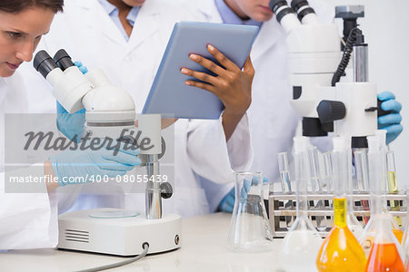 Scientists working with microscope and tablet in laboratory