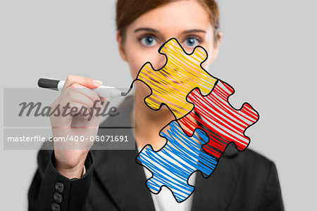 Businesswoman drawing a puzzle on a glass board