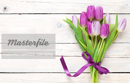Purple tulip bouquet over wooden table with copy space
