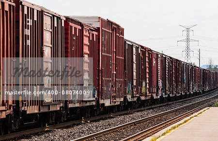Line of red freight train boxcars in perspective parallel to tracks.