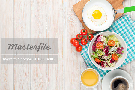 Healthy breakfast with fried egg, toasts and salad on white wooden table. Top view with copy space