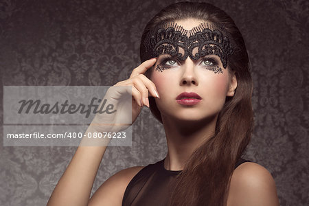 Beautiful, gorgeous, stunning brunette woman with long hair. Wearing transparent, black mask dark make up with little pattern and pink lips.