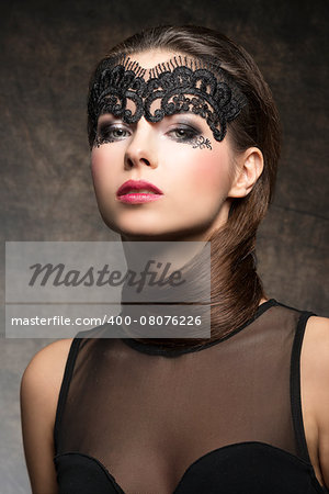 Beautiful, gorgeous, stunning brunette woman with hairstyle near neck and transparent mask on the face, make up is dark with pink lips. She is wearing black transparent top.