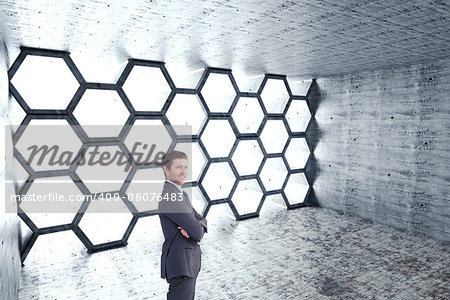 Businessman standing with arms crossed against hexagon room