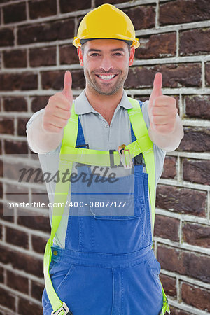 Builder in safety gear against red brick wall