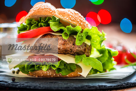 Closeup of Homemade Hamburger with Fresh Vegetables and Lights in Background