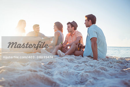 Happy hipsters relaxing and playing guitar at the beach