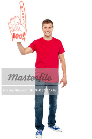 Casual guy showing large pointy boo hurray hand toy. Full length portrait