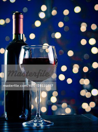 red wine glass near bottle with light blue bokeh in background