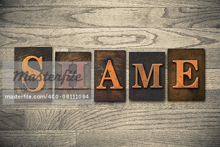 The word "SHAME" theme written in vintage, ink stained, wooden letterpress type on a wood grained background.