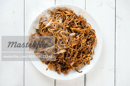 Asian dish stir fried char kuey teow over wooden background.  Fresh cooked with hot steams.