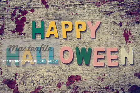 The colorful words "HAPPY HALLOWEEN" made with wooden letters on old wooden board.