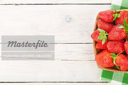 Fresh ripe strawberry in bowl over wooden table background. Top view with copy space