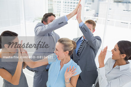 Excited business team cheering in the office