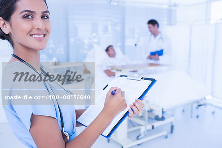 Smiling doctor checking patients file in hospital room