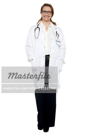 Full length portrait of a cheerful female doctor with hands in lab coat pocket.