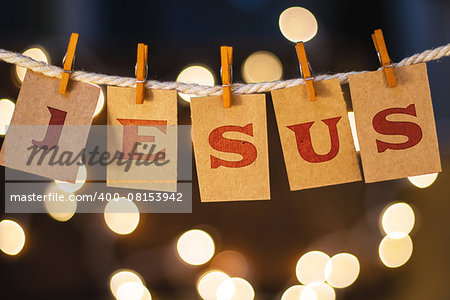 The name JESUS printed on clothespin clipped cards in front of defocused glowing lights.