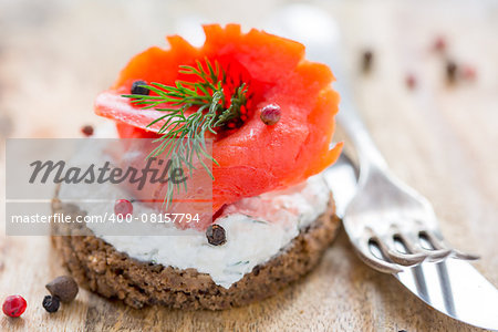 Sandwich with salted red salmon and black bread close up.