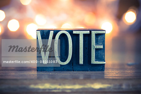 The word VOTE written in vintage metal letterpress type on a soft backlit background.