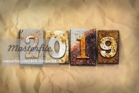 The word "2019" written in rusty metal letterpress type on a crumbled aged paper background.