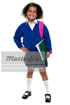 Girl in smart uniform holding notebook and calculator in hand and carrying pink backpack over shoulders.