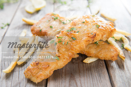 Fish and chips. Fried fish fillet with french fries on old wooden background. Fresh cooked with hot steams.