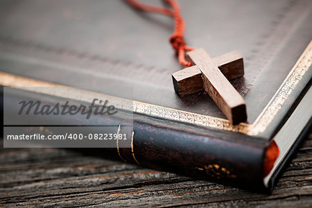 Closeup of simple wooden Christian cross necklace on holy Bible