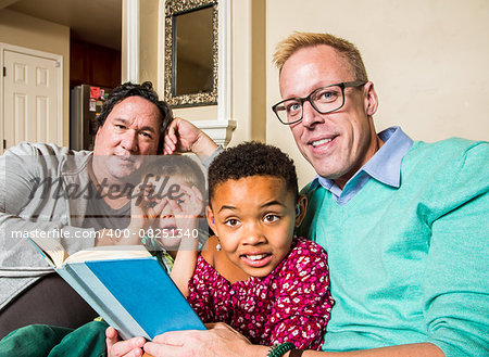 Attractive gay couple reads a book to their children