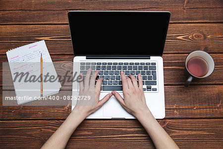 Woman working with laptop placed on the wooden desk