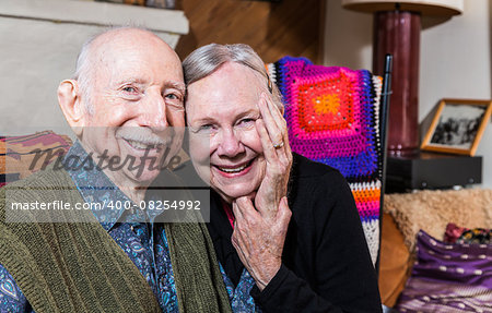 Smiling couple sitting together in living-room touching hands
