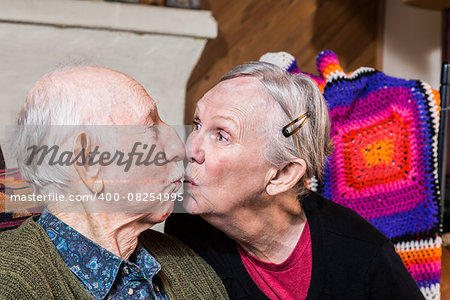 Happy elderly couple sitting in livingroom kissing