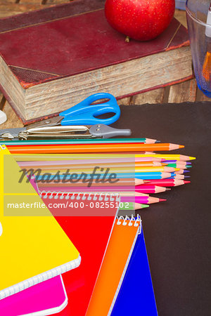 Set of colorful pencils with book and notebooks on black board