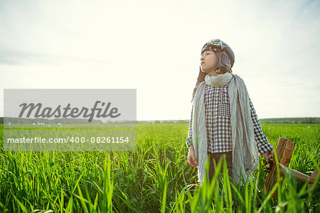 Little boy with wooden airplane in the field